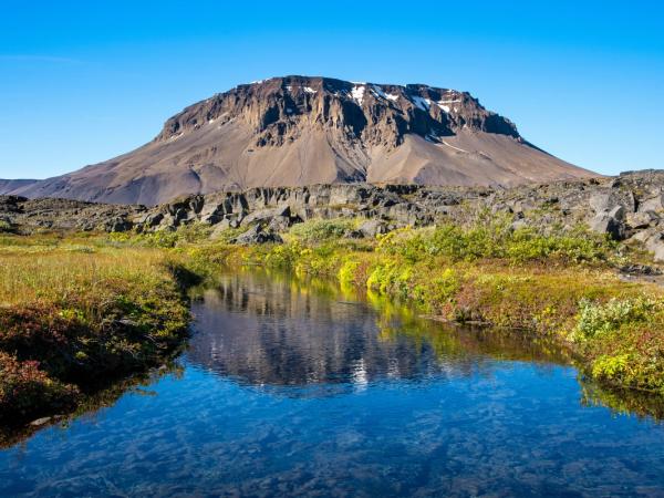 there is a mountain in the background and a river in the foreground .