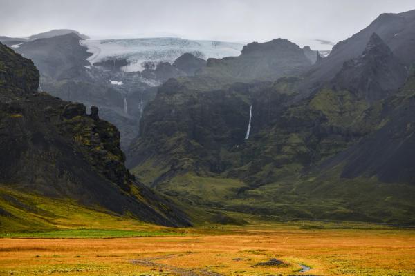 hay una cascada en medio de las montañas en el fondo.