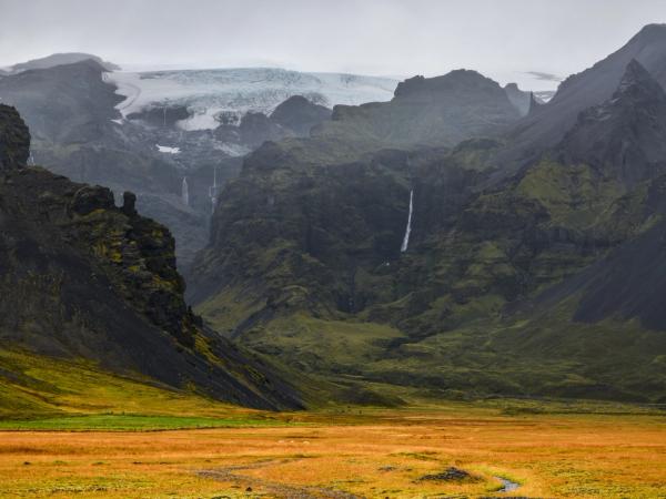 there is a waterfall in the middle of the mountains in the background .