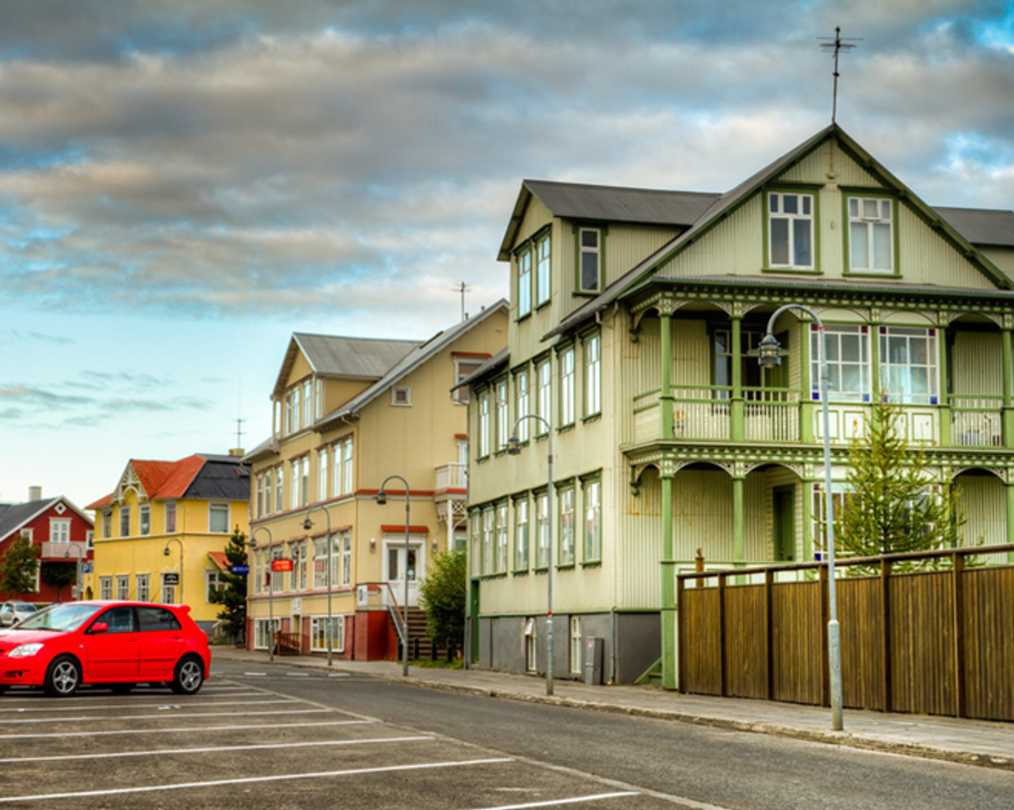 un coche rojo está aparcado frente a una casa verde en el casco antiguo de Akureyri en Islandia.
