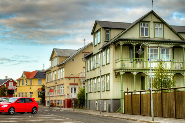 un coche rojo está aparcado frente a una casa verde en el casco antiguo de Akureyri en Islandia.