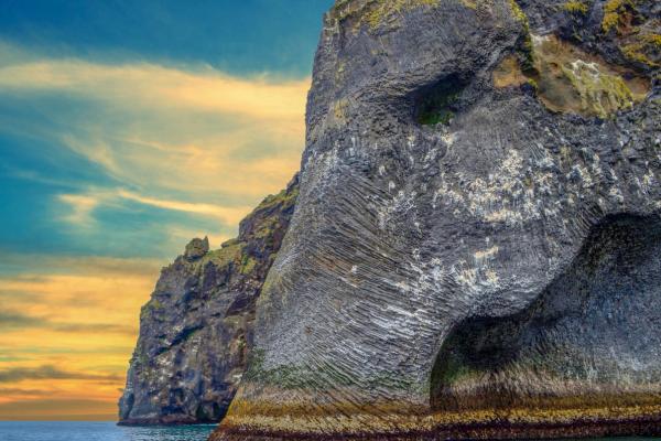 a large rock formation shaped like an elephant 's head is in the middle of the ocean .