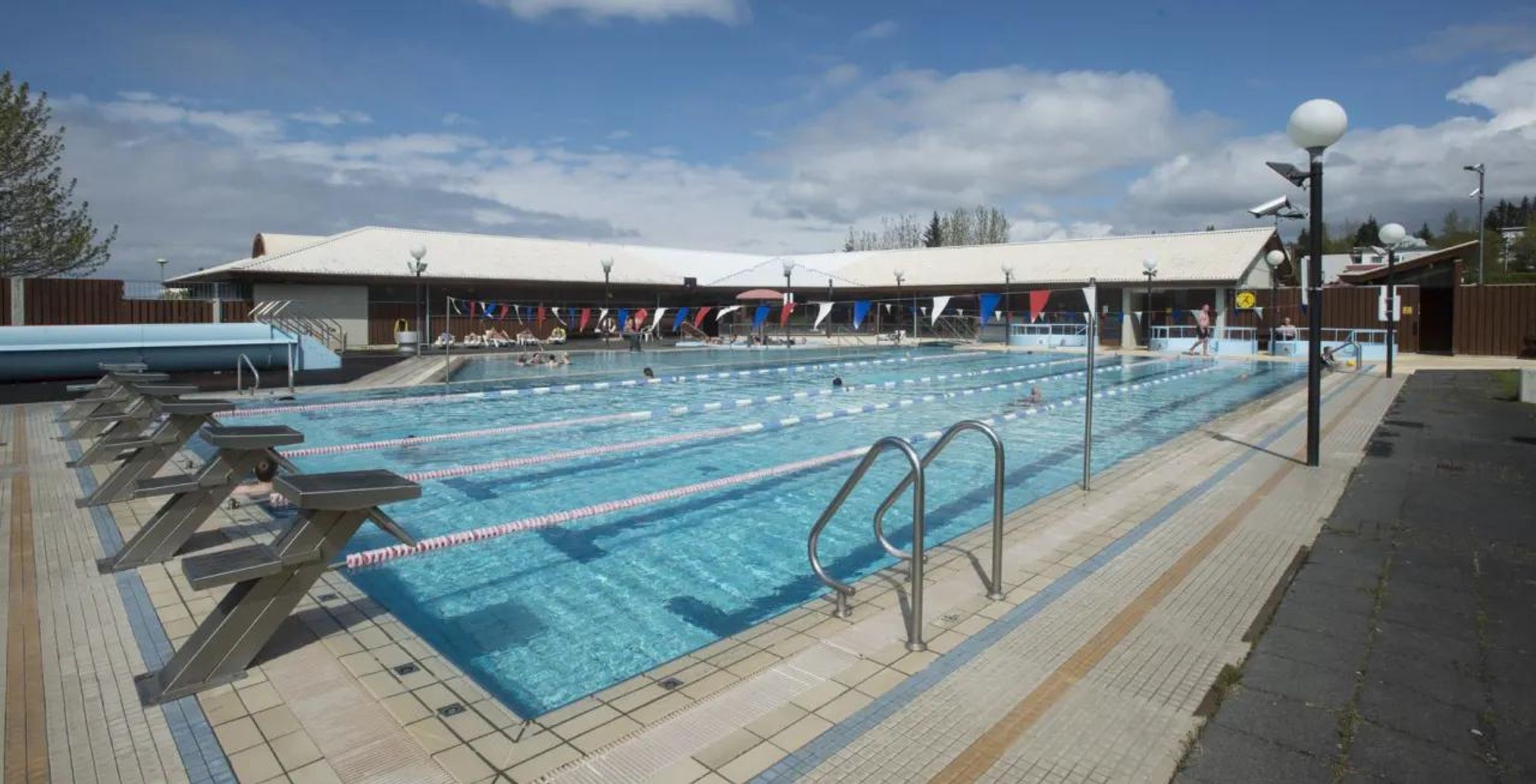 a large swimming pool with a building in the background and people swimming in it .