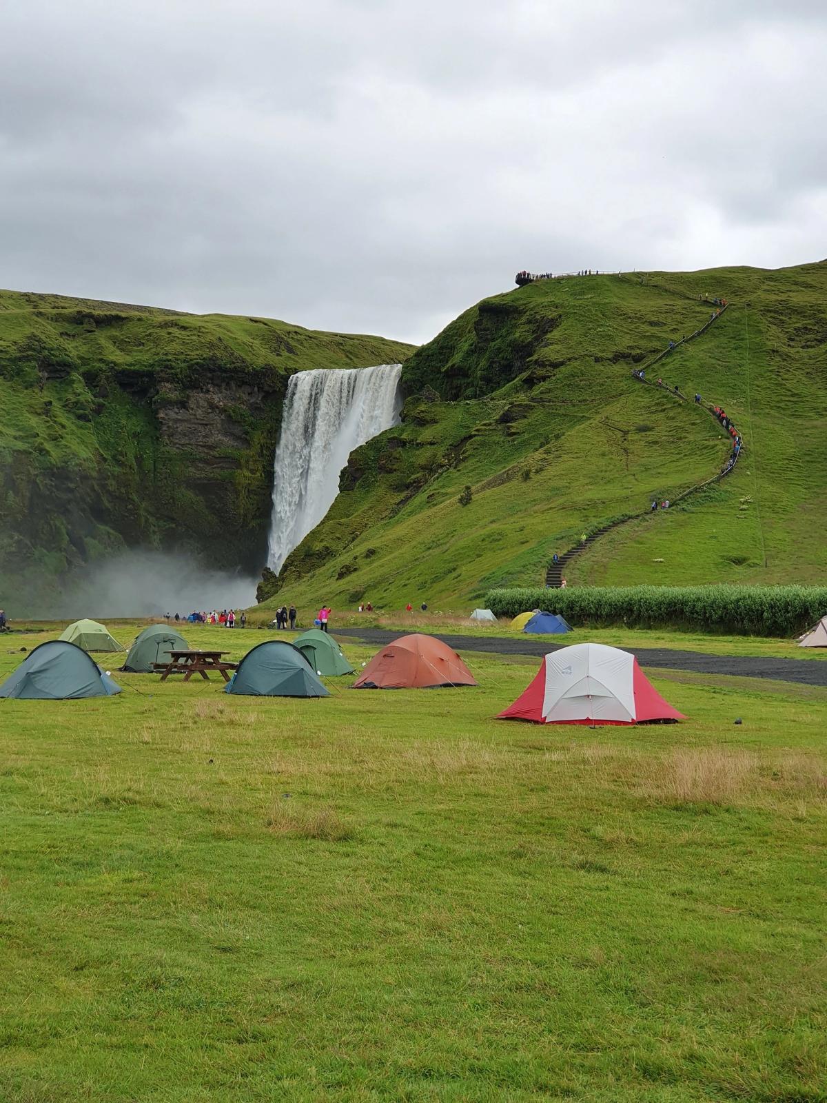 a group of tents are set up in front of a waterfall