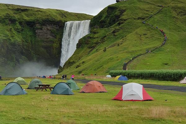 a group of tents are set up in front of a waterfall
