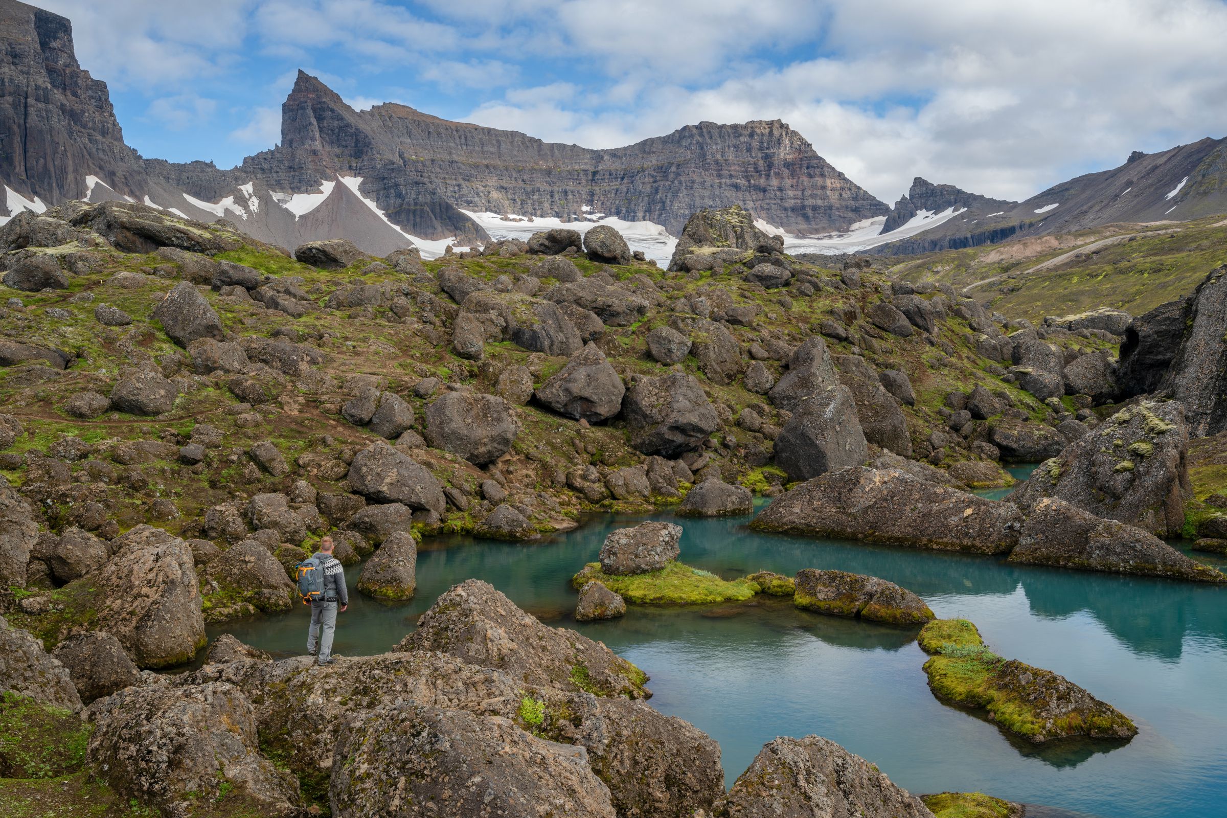 un hombre está parado sobre una roca cerca de un lago en las montañas .