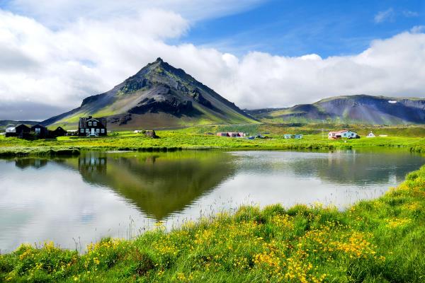 paisaje de una montaña reflejada en un lago rodeado de hierba verde