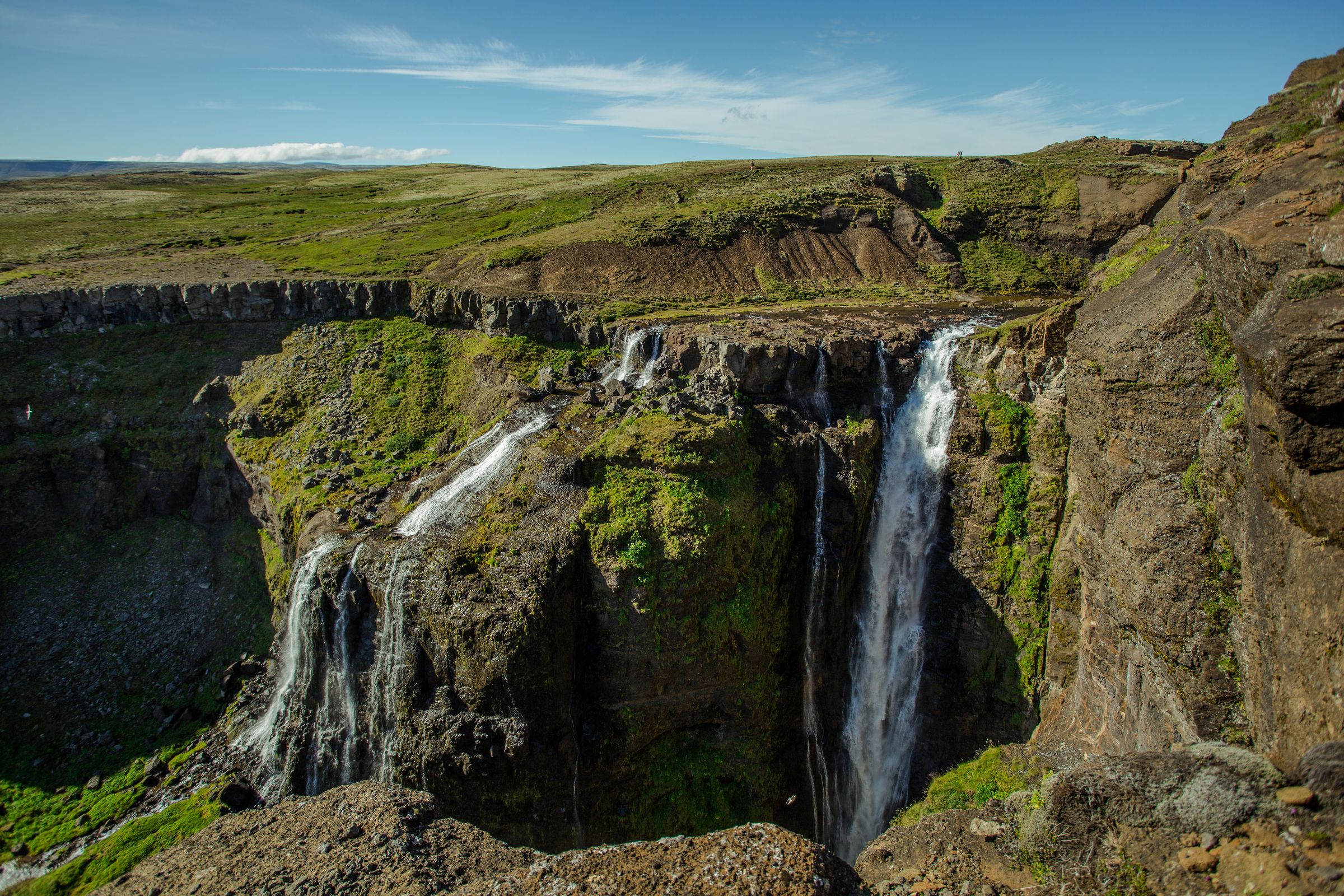 there is a waterfall in the middle of a canyon at Glymur In Iceland.