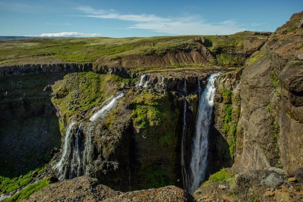 there is a waterfall in the middle of a canyon at Glymur In Iceland.
