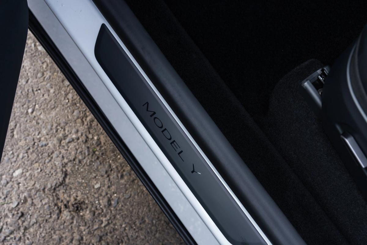 Emblema para el umbral de la puerta del Model Y Umbral de la puerta de un Tesla Model Y con el emblema Model Y, aparcamiento de grava de una empresa de alquiler de coches en Islandia