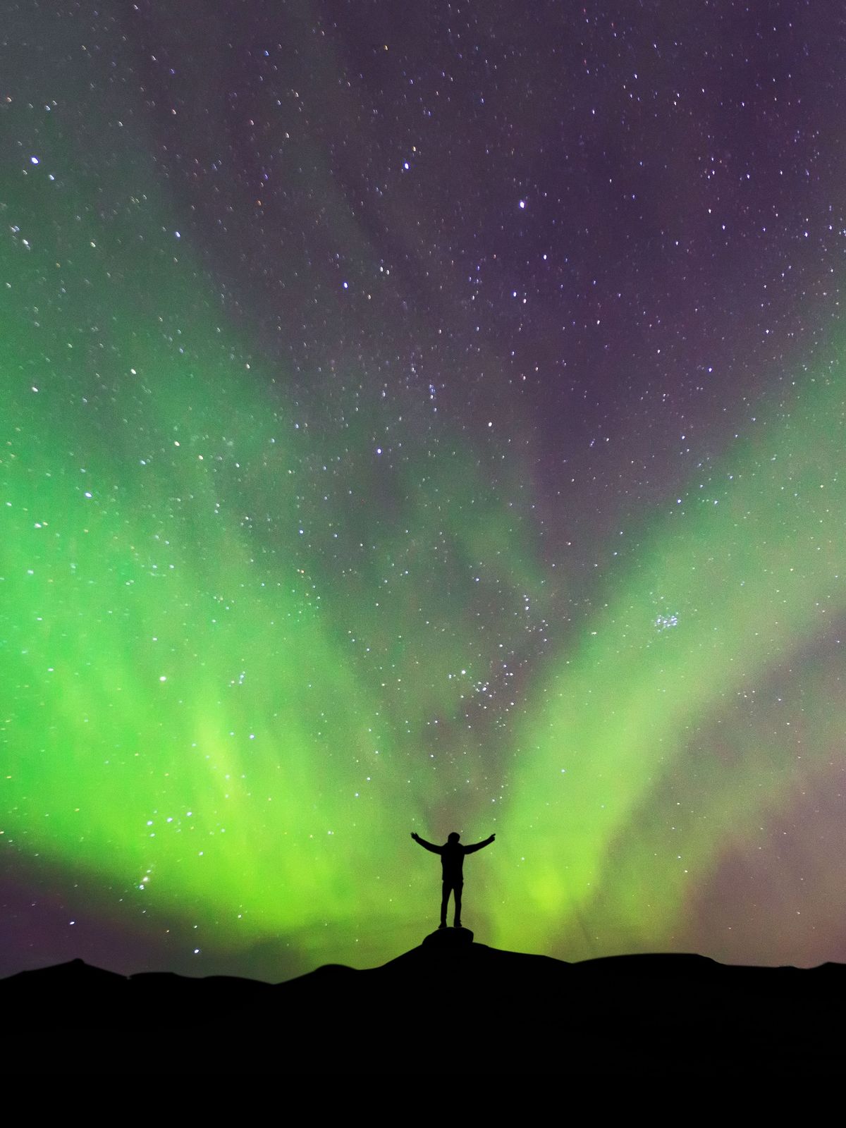Man standing in front of the Northern Lights in Iceland