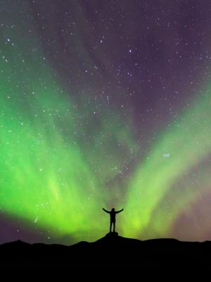 Man standing in front of the Northern Lights in Iceland
