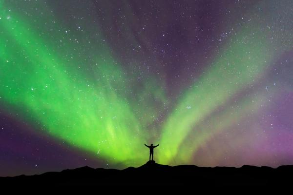 Hombre bajo la aurora boreal en Islandia