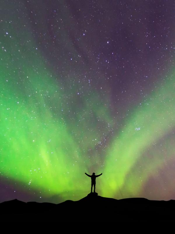Man standing in front of the Northern Lights in Iceland