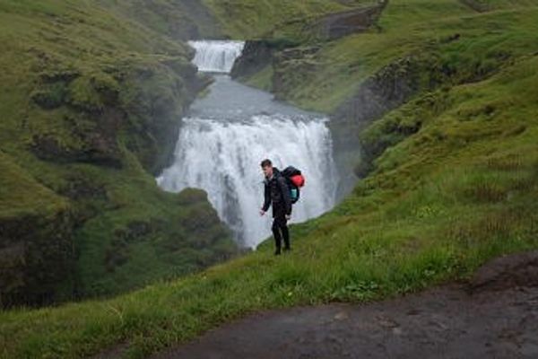 Chico caminando por delante de una cascada