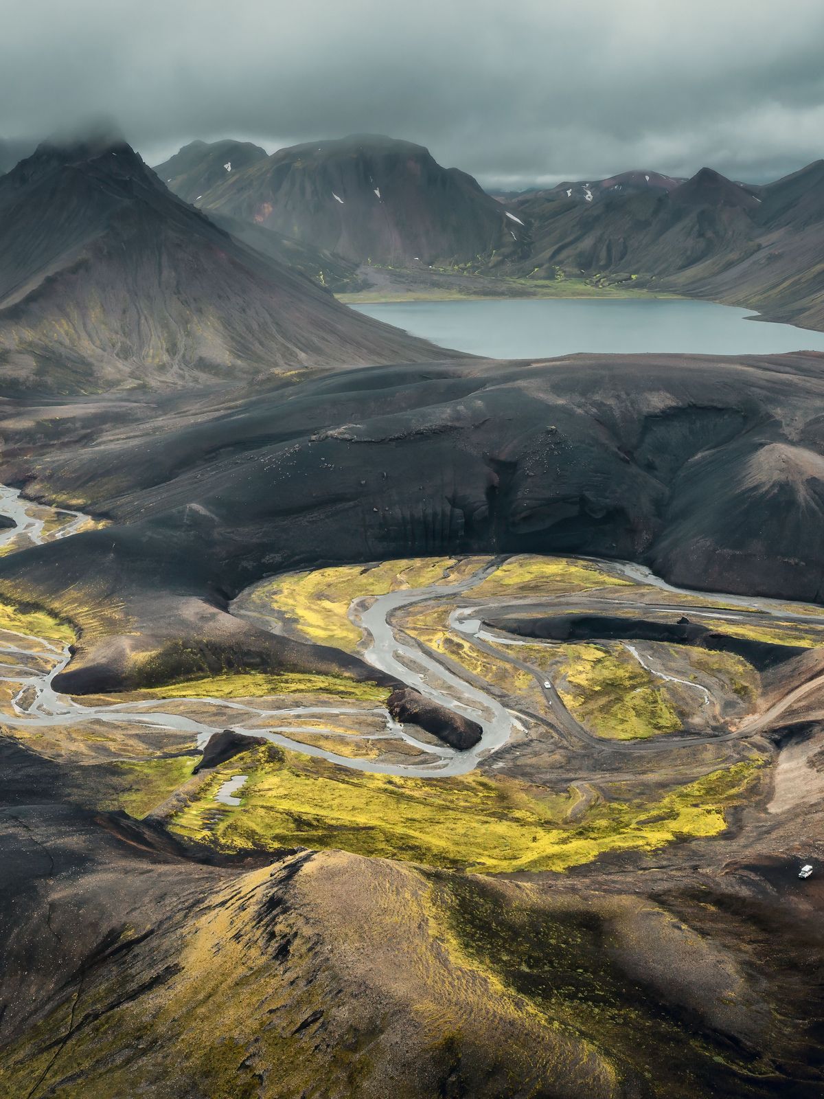 an aerial view of a mountain landscape with a lake and a road .