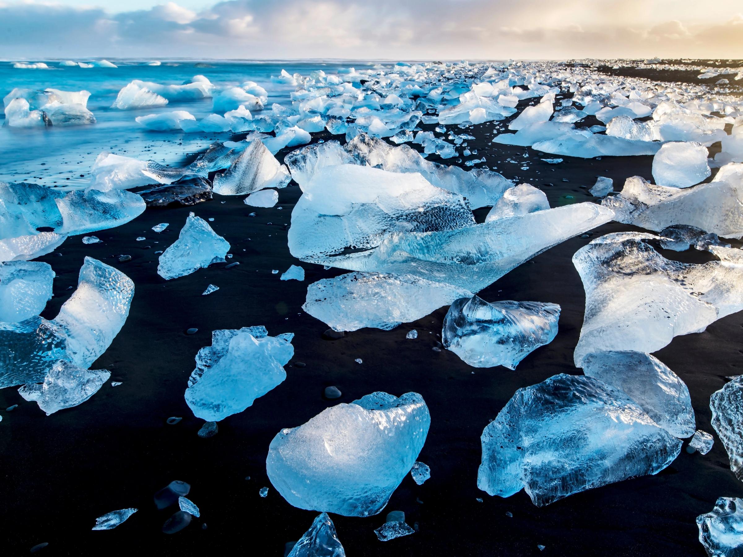 grandes trozos de hielo sobre la arena negra de una playa islandesa