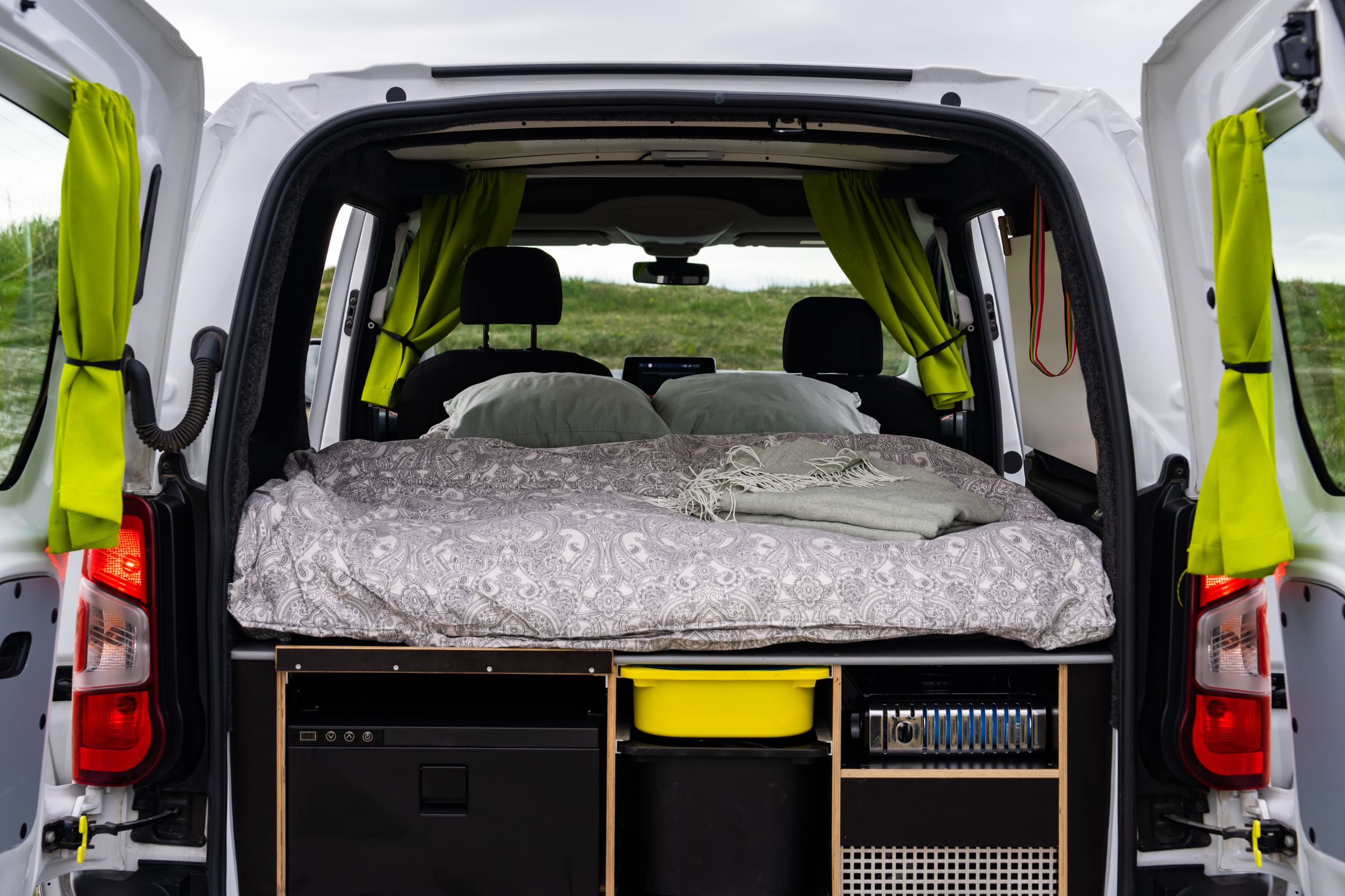 Cama accesible por las puertas traseras Las puertas traseras se abren y dan acceso a una cama con 2 almohadas, cortinas laterales y compartimentos de almacenamiento debajo.