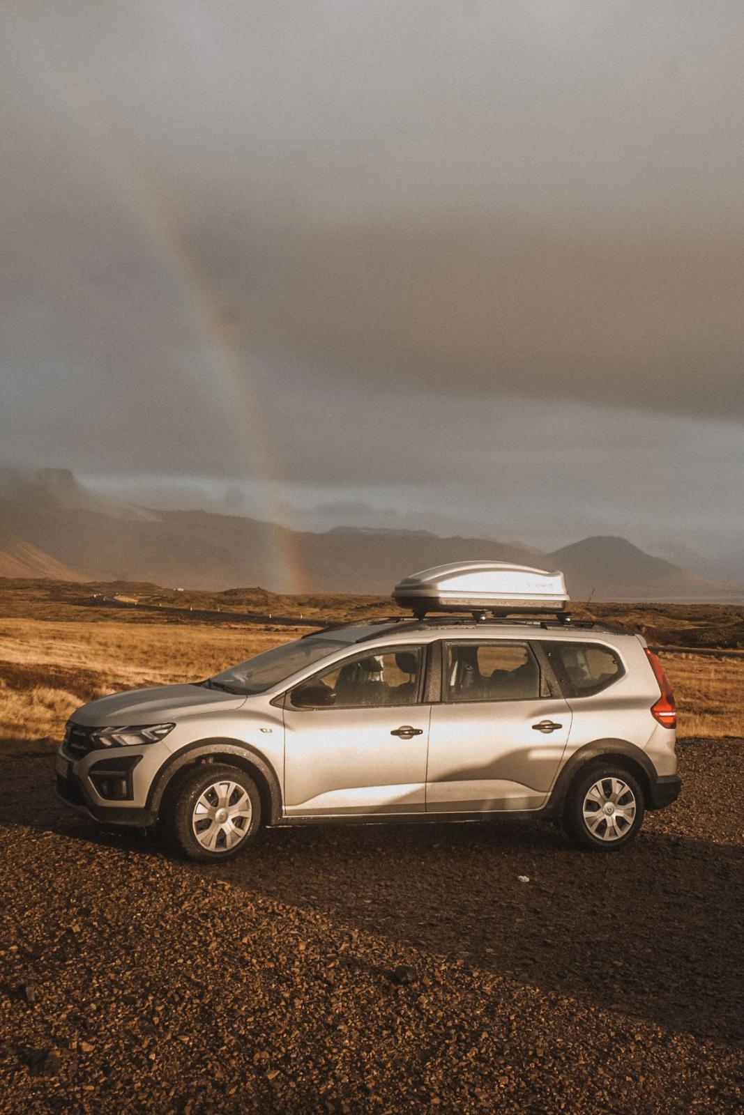 Dacia Jogger with a rood box parked with a rainbow in the background