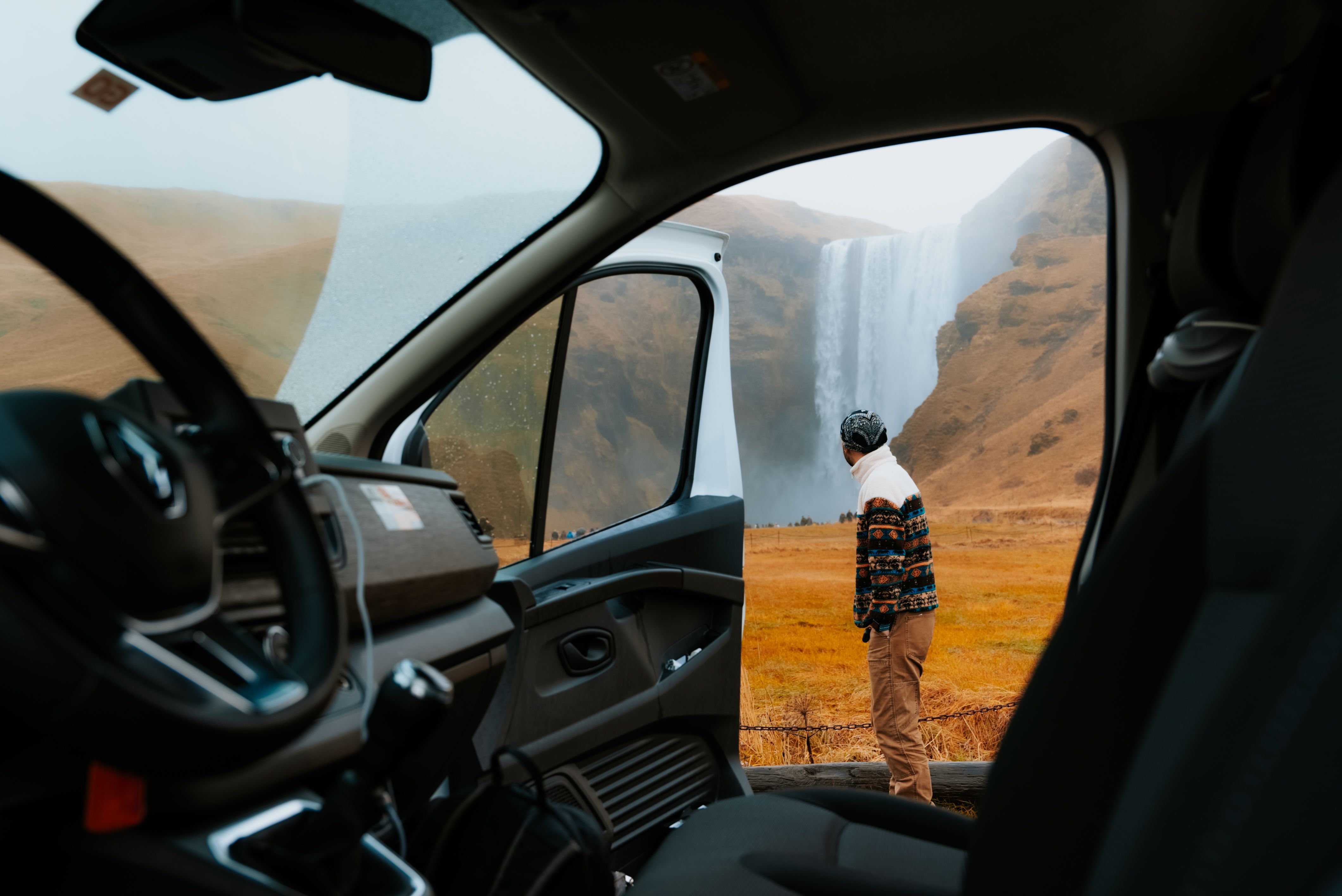 a man is standing in front of a waterfall in a van .