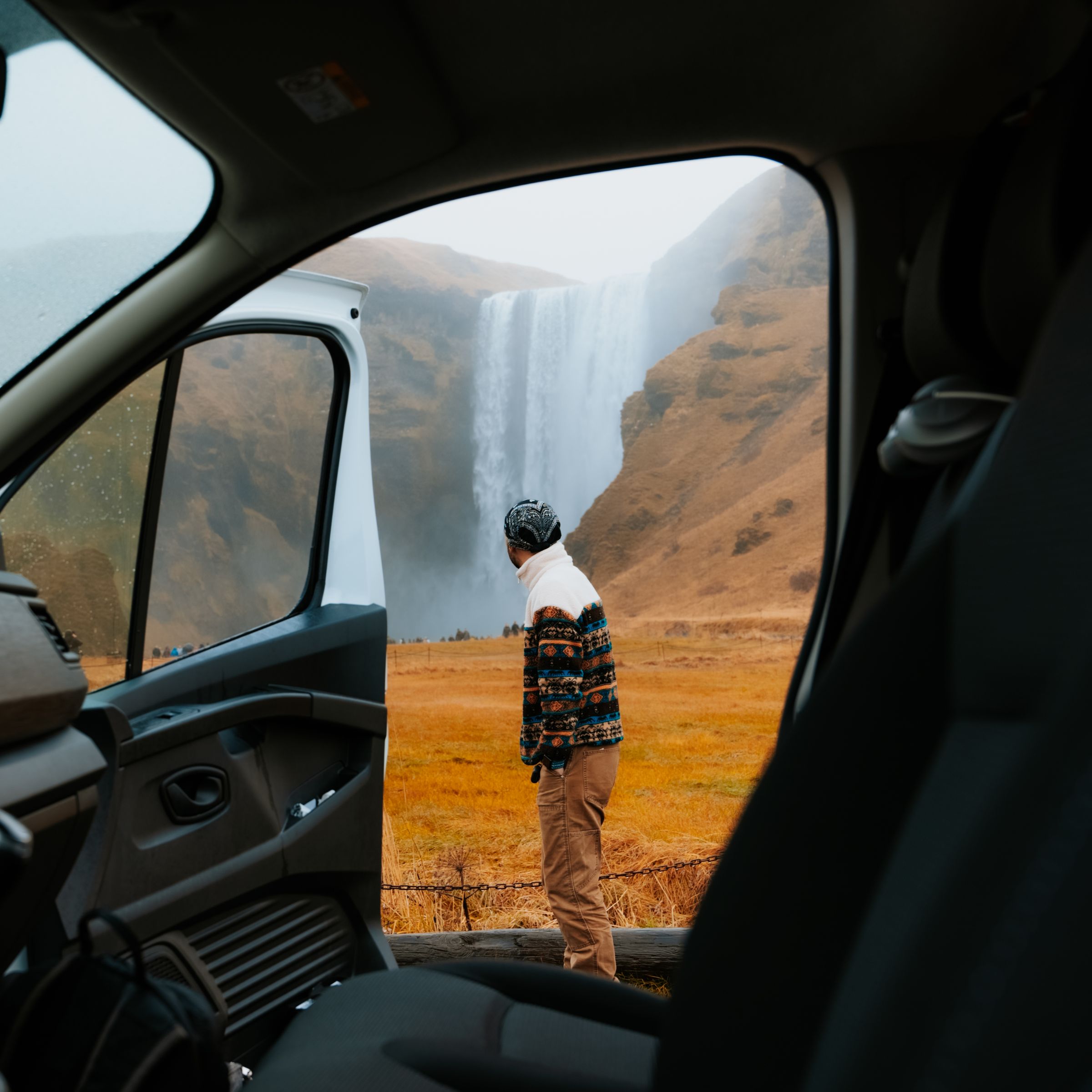 a man is standing in front of a waterfall in a van .