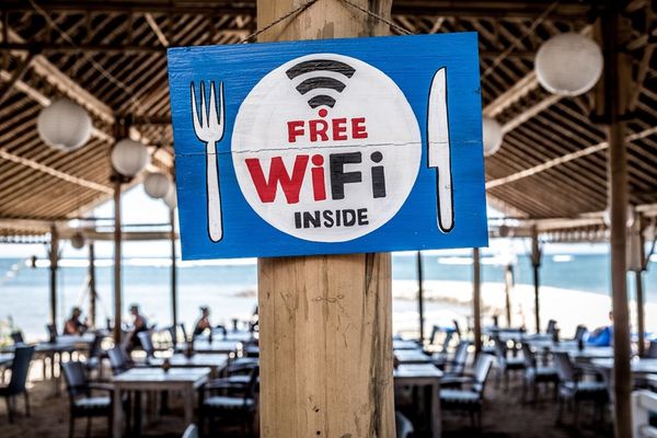 a blue and white sign that says `` free wifi inside '' is hanging on a wooden pole in iceland. in a restaurant .