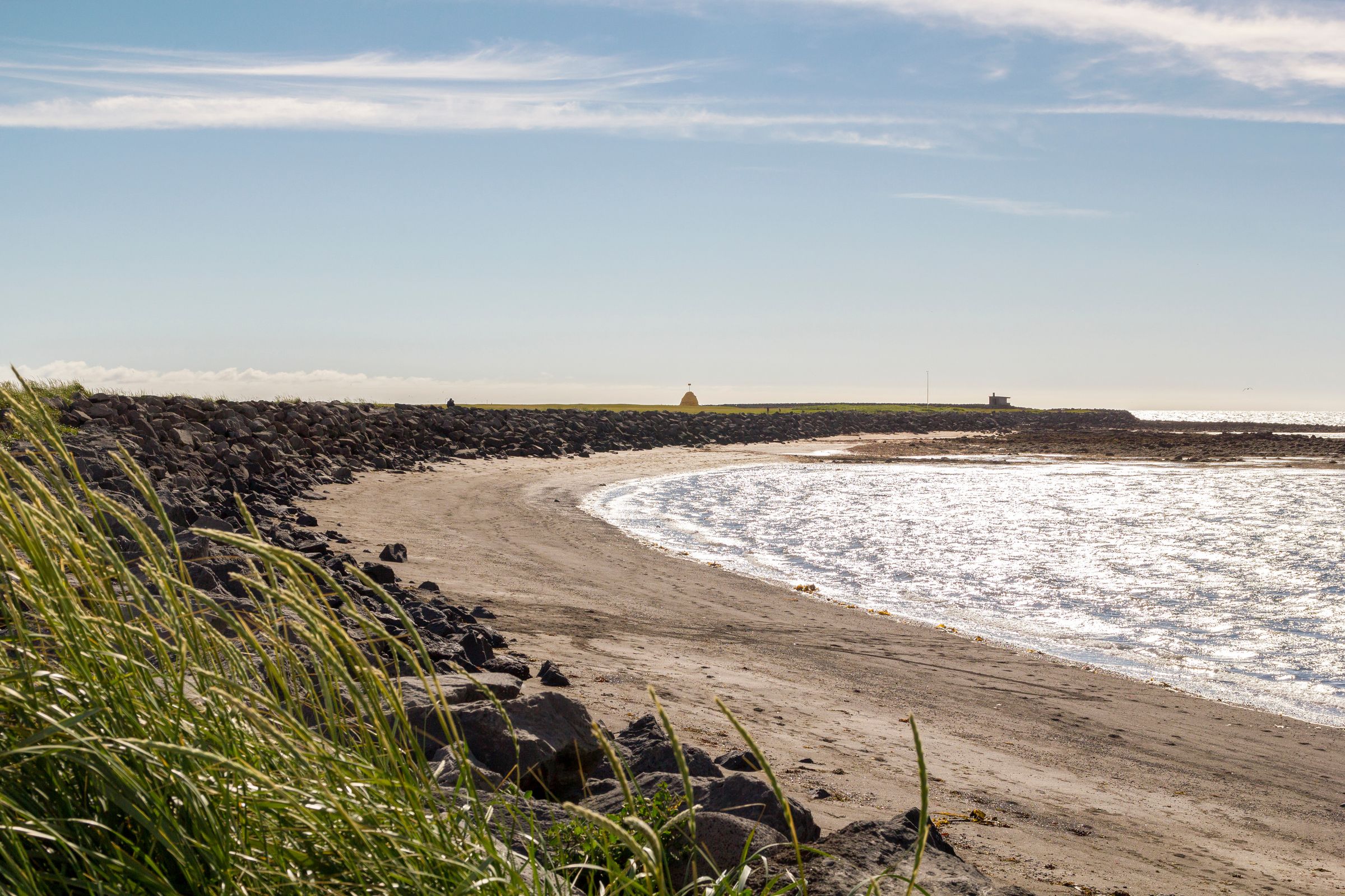 una playa de arena blanca con rocas y hierba