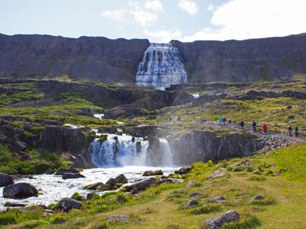 Panoramic of Dynjandi Waterfall with a group of people walking towards it