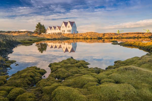 A house is reflected in the water of a lake.