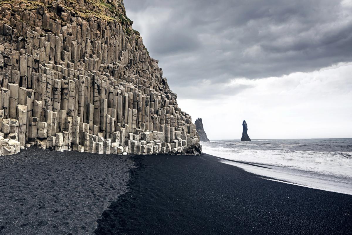 Playa de arena negra y columnas de basalto