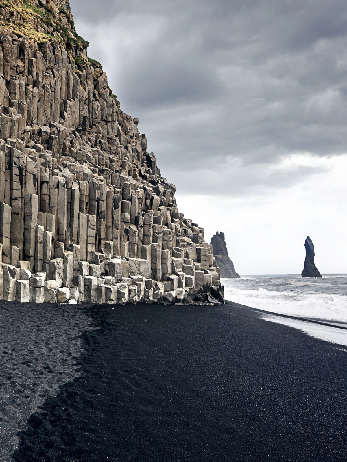 Playa de arena negra y columnas de basalto