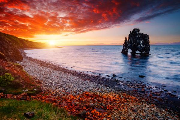 una formación rocosa en medio del océano al atardecer.