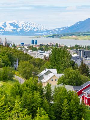 a red house is sitting on top of a hill next to a body of water .