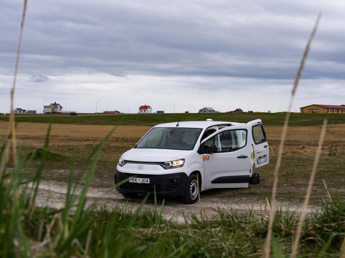 Puertas abiertas de la autocaravana compacta Una autocaravana compacta para 2 personas en un camino de grava, con las puertas abiertas, alquiler de autocaravanas en Islandia