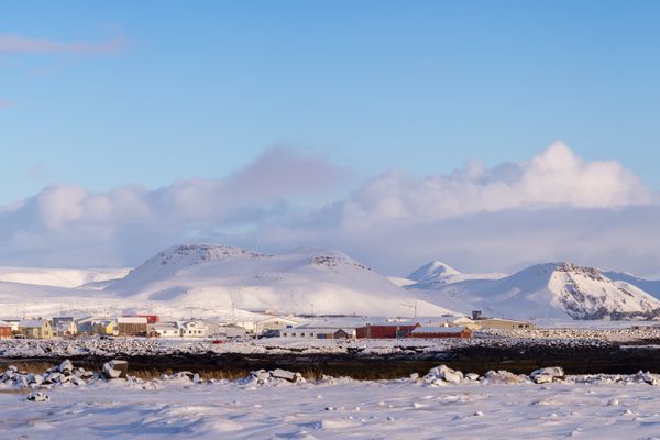 a snowy field with mountains in the background and a blue sky
