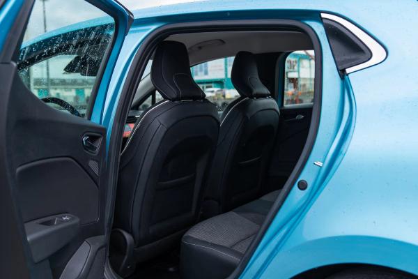 Open rear door of a light blue car, showing the interior with black seats.