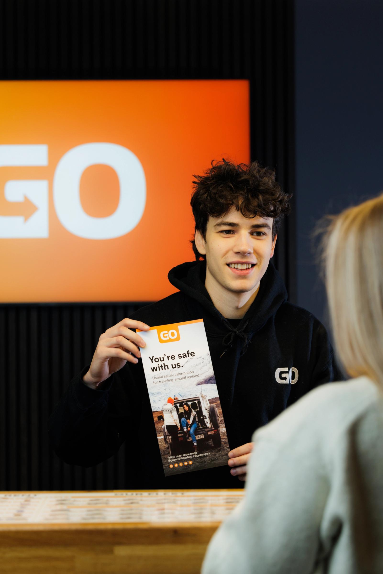 a person handing a car key to another person in front of a sign that says go