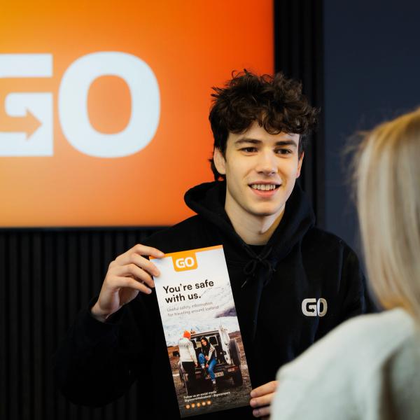 a person handing a car key to another person in front of a sign that says go