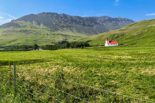 White and red church in the middle of a green valley