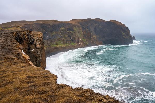 a cliff overlooking the ocean with waves crashing on the shore in ketubjörg cliffs in iceland.
