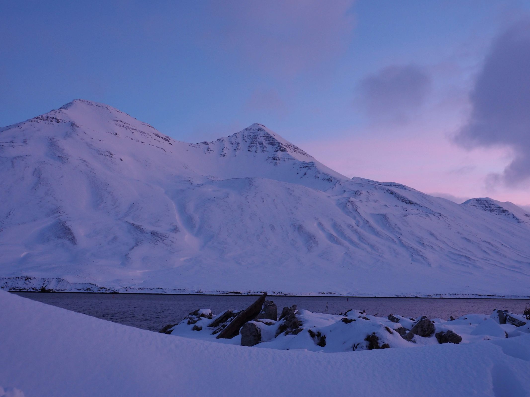 a snowy mountain with a lake in the foreground in iceland.