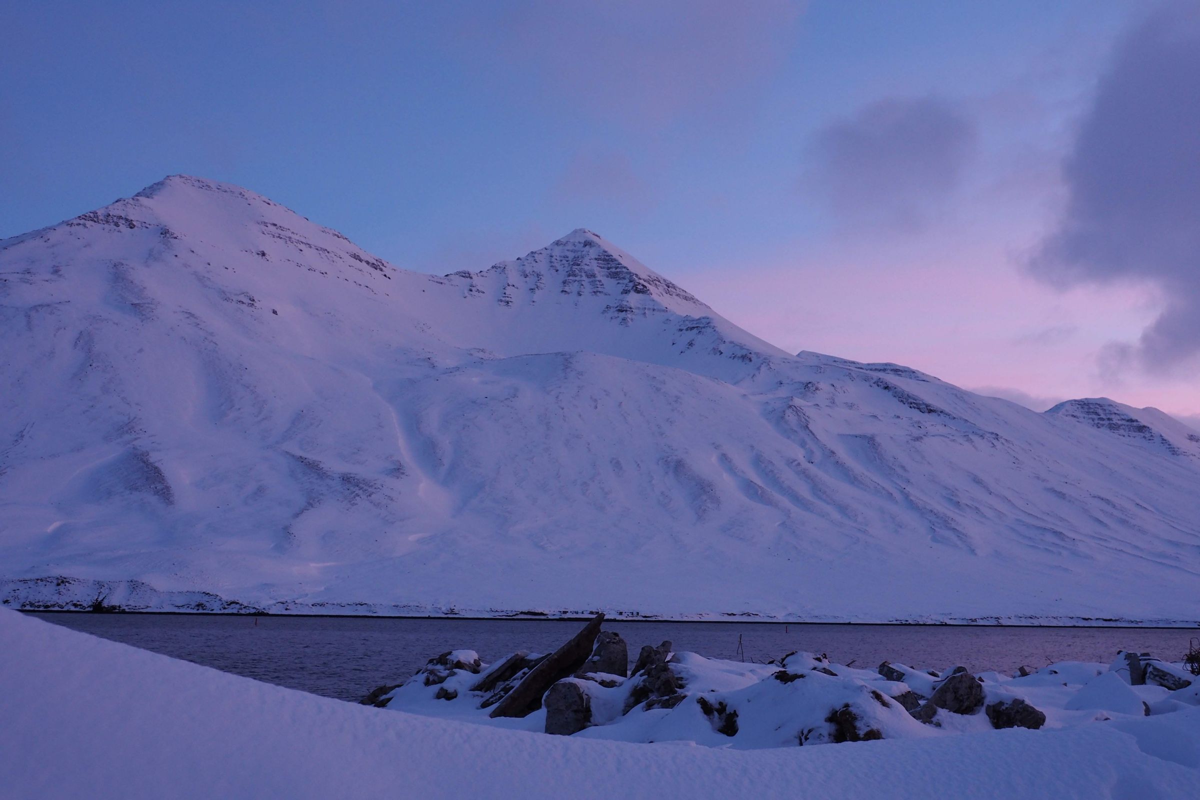 a snowy mountain with a lake in the foreground in iceland.