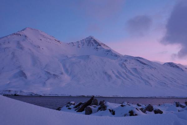a snowy mountain with a lake in the foreground in iceland.