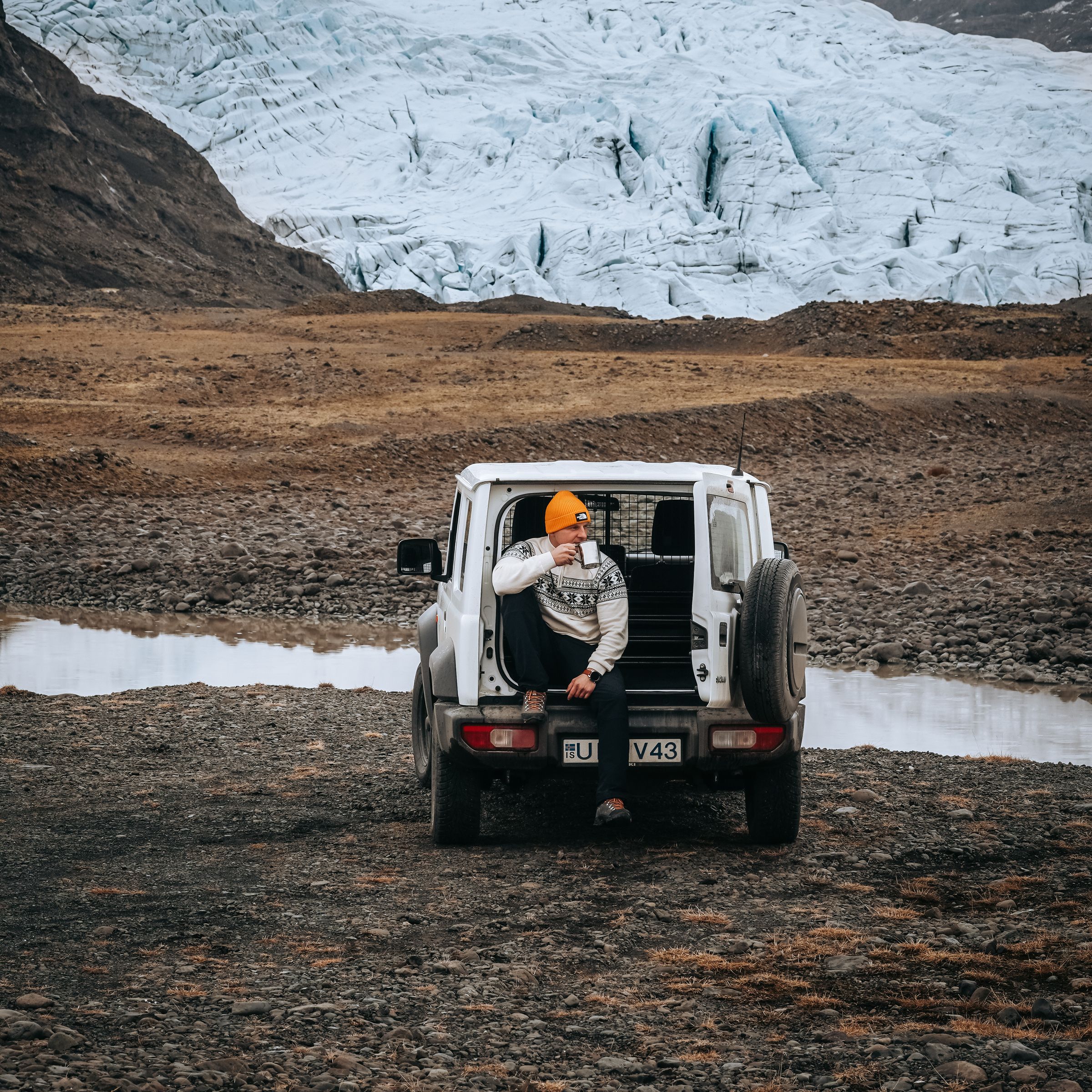 a man sits in the back of a white jeep with the license plate v43