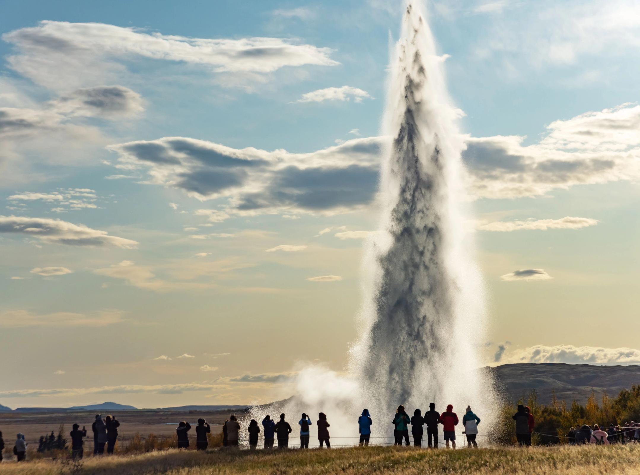 Decenas de turistas admirando el geyser Strokkur mientras este lanza agua hacia arriba