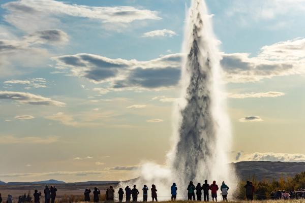 Decenas de turistas admirando el geyser Strokkur mientras este lanza agua hacia arriba