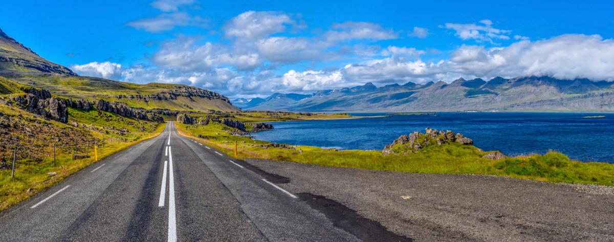 a road going through a valley with mountains and a lake in the background .
