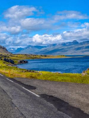 a road going through a valley with mountains and a lake in the background .
