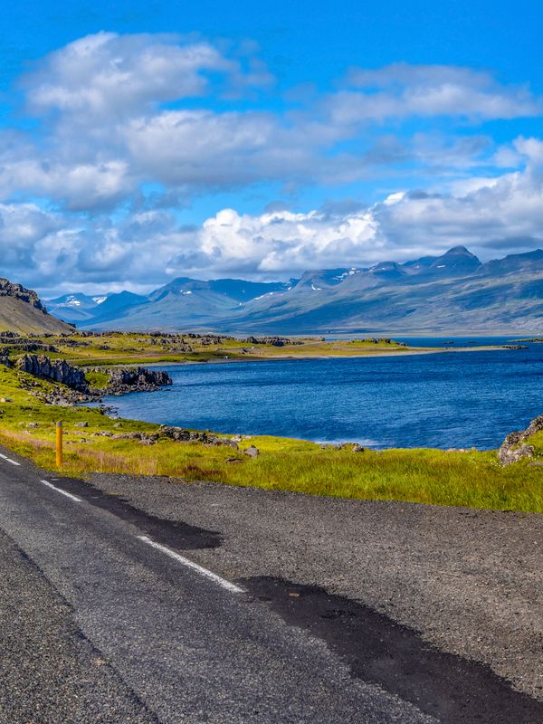 a road going through a valley with mountains and a lake in the background .