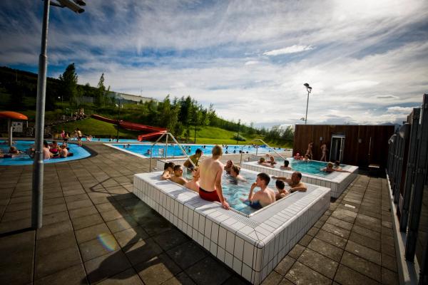 Photo Credit: sundlaugar.is a group of people are sitting in a large swimming pool .